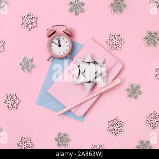 Natale decorazioni invernali, business note book con sveglia, fiocchi di neve e la prua su sfondo rosa. Foto Stock