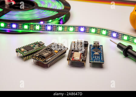 Selezione di piccole schede di sviluppo visualizzata con una striscia di LED, il metro e il ponticello dello sfondo. Schede madri includono minuscolo, piume, esp8266 e nano. Foto Stock