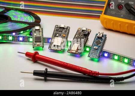 Selezione di piccole schede di sviluppo visualizzata con una striscia di LED, il metro e il ponticello dello sfondo. Schede madri includono minuscolo, piume, esp8266 e nano. Foto Stock