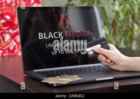 La ragazza si siede a un computer portatile e fa acquisti su internet sul venerdì nero. Veloce e semplice concetto di trading Foto Stock