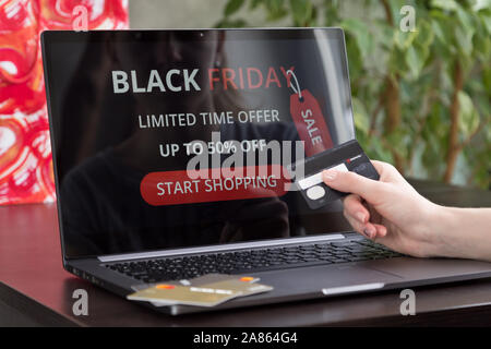 La ragazza si siede a un computer portatile e fa acquisti su internet sul venerdì nero. Veloce e semplice concetto di trading Foto Stock