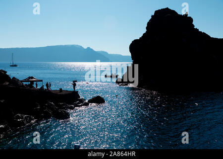 I turisti sulle rocce e le barche nei pressi di Amoudi Bay sull isola di Santorini in Grecia. Foto Stock