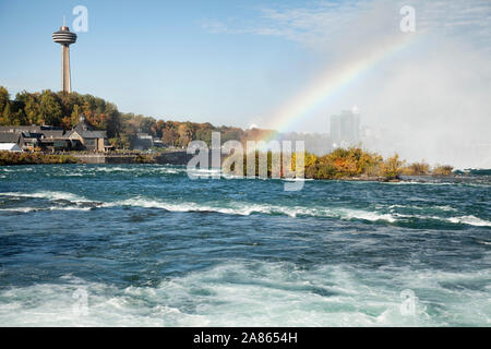 Visualizza in basso il fiume Niagara verso le cascate Horseshoe che mostra un arcobaleno sopra le cascate e la Torre Skylon in background Foto Stock