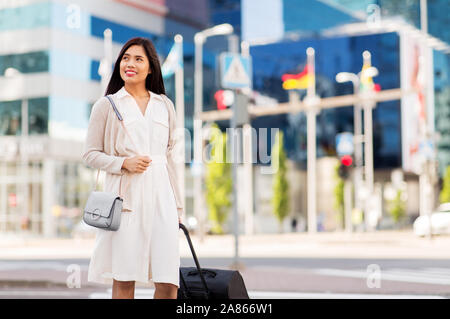 Felice giovane donna asiatica con borsa da viaggio in città Foto Stock