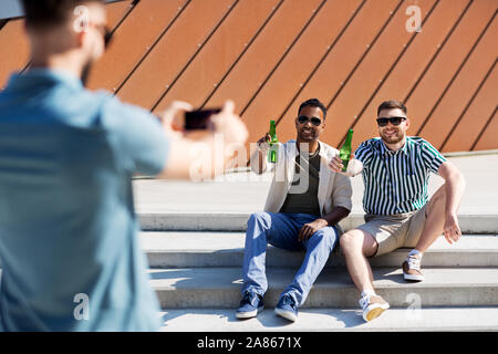 Uomo di fotografare gli amici a bere una birra su strada Foto Stock