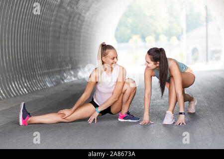 Le donne con fitness trackers stretching all'aperto Foto Stock