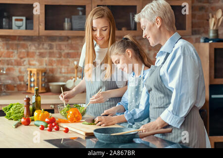 Adulto felice ladies insegnamento bambina come cucinare Foto Stock