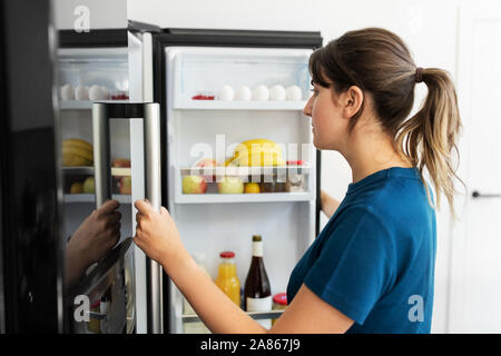 Donna ad aprire il frigo a casa cucina Foto Stock