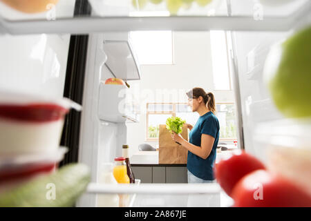 Vista di donna con cibo acquistato da casa frigo Foto Stock