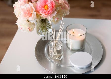 Aroma diffusore reed, candela e fiori sul tavolo Foto Stock