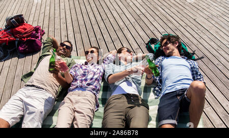 Gli amici a bere la birra e il sidro di mele sulla terrazza in legno Foto Stock