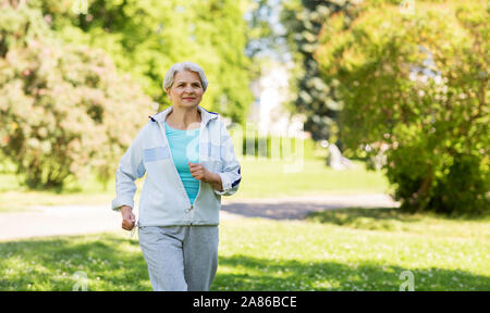 Senior donna che corre lungo il parco di estate Foto Stock