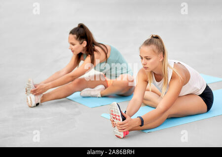 Le donne con fitness trackers stretching all'aperto Foto Stock