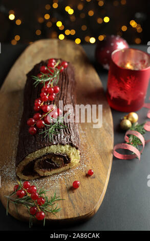 Natale al cioccolato Yule Log, Buche de Noel sul tagliere di legno. Decorazione di natale su sfondo scuro. Primo piano Foto Stock