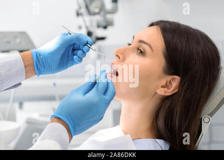 Ravvicinata di una giovane donna che guarda al dentista con fiducia Foto Stock