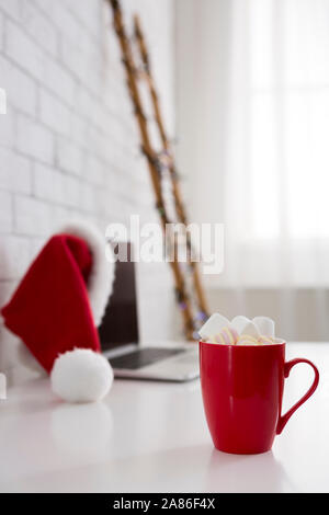 Laptop moderno per il lavoro e per la tazza di cioccolato sulla tavola bianco Foto Stock