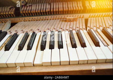 Polveroso vecchio pianoforte con tasti rotti e illuminazione calda Foto Stock