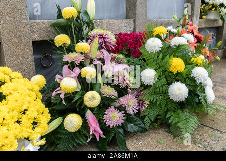Bouquet di fiori colorati durante christian tutti i santi giorni della manifestazione che giace nella tomba nel cimitero. Concetto di morte Foto Stock