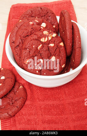 Freschi di forno degustazione ricco di velluto rosso a Natale e la festa del Ringraziamento i cookie con un trito di noci di macadamia servito in una ciotola bianco. Foto Stock