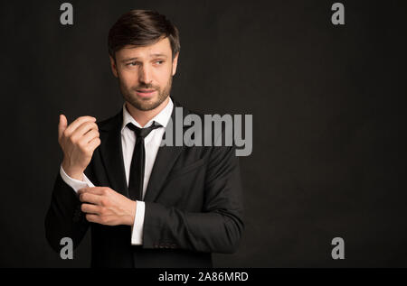 Bello imprenditore nel soddisfare abbottonatura Manica in piedi in Studio Foto Stock