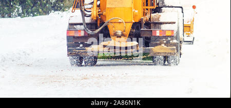 Auto comunale spruzza strade innevate con sabbia e sale. Lo spalaneve. Inverno anti-slittamento su strada il concetto di manipolazione Foto Stock