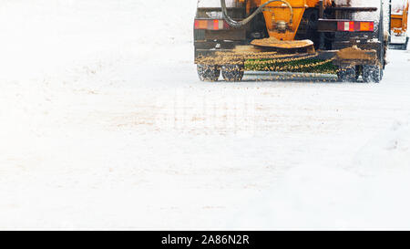 Auto comunale spruzza strade innevate con sabbia e sale. Lo spalaneve. Inverno anti-slittamento su strada il concetto di manipolazione. Copia spase Foto Stock