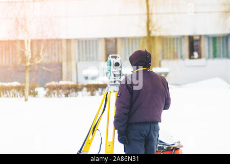 Ingegnere geometra utilizza una stazione totale in corrispondenza di un sito in costruzione. Rilevamenti geodetici. Costruzione Edilizia Foto Stock