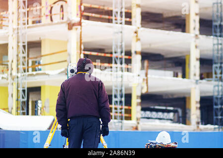 Ingegnere geometra utilizza una stazione totale in corrispondenza di un sito in costruzione. Rilevamenti geodetici. Costruzione Edilizia Foto Stock