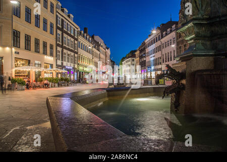 COPENHAGEN, Danimarca - 22 Maggio 2017: Viste lungo la via pedonale Stroget durante la notte con la cicogna Fontana (Storkespringvandet) in primo piano. Persone e resta Foto Stock