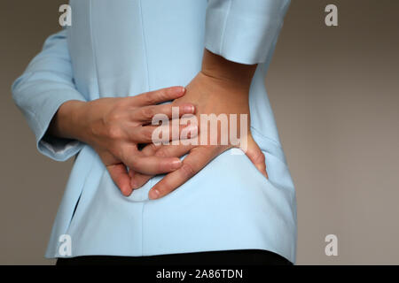 Dolore nel lato, donna in tuta di office che soffrono di mal di schiena. Mani femminili holding posteriore inferiore, concetto di rene o di malattia della colonna vertebrale Foto Stock