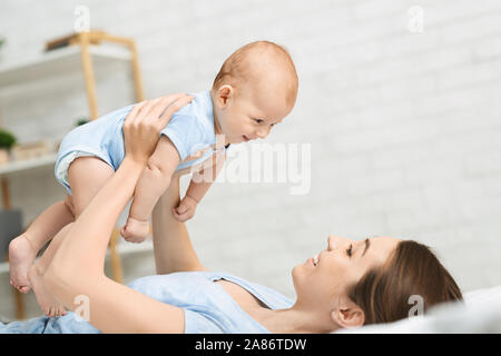 Amorevole Madre giocando con il neonato su letto di casa Foto Stock