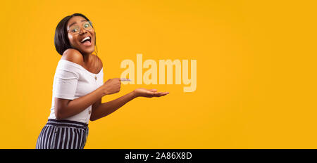 Ragazza puntare il dito a aprire Palm Standing, Studio Shot, Panorama Foto Stock