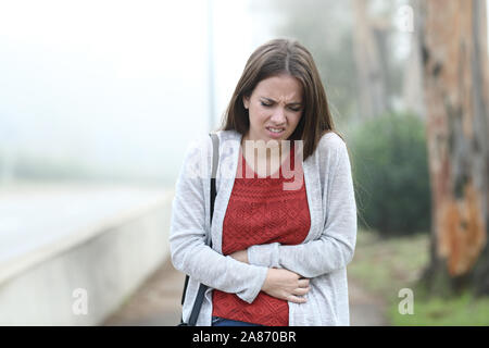 Vista frontale ritratto di una donna che soffriva il mal di pancia di un nebbioso giorno Foto Stock