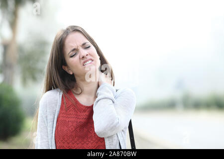 Vista frontale ritratto di una donna che soffriva il mal di collo un nebbioso giorno Foto Stock