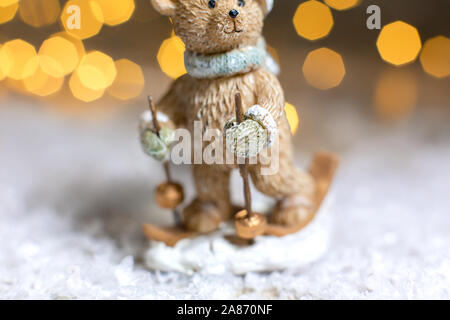 Decorazione di Natale figurine a tema. Statuetta di un orso di peluche di sci. Decorazione per albero di Natale. Decorazioni festive, calde luci bokeh di fondo Foto Stock