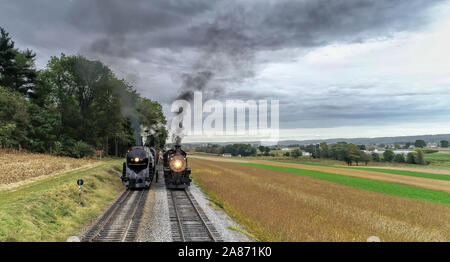 Strasburgo, Pennsylvania, Ottobre 2019 - 2 antiche di Norfolk e Western Motori a vapore la cottura a vapore fino a fianco a fianco sbuffando fumo nero e il vapore Foto Stock