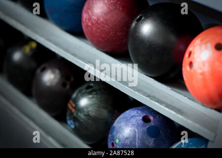 Più palle da bowling allineate in un rack di stoccaggio. Foto Stock