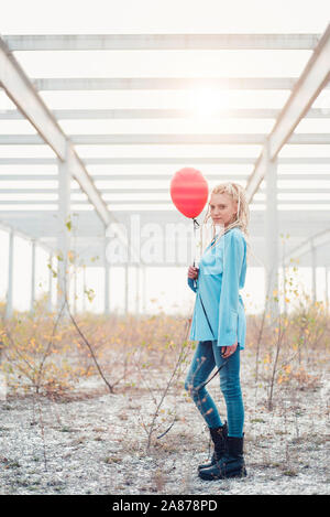 Giovane donna bionda con dreadlocks e azienda palloncino rosso Foto Stock
