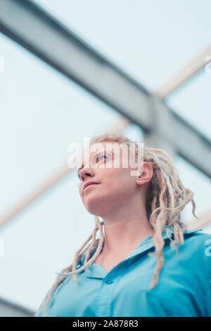Giovane donna bionda con dreadlocks e maglietta blu basso angolo verticale Foto Stock