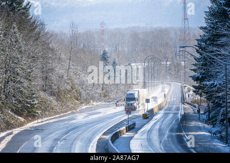 Big Rig white long haul semi carrello con la protezione della griglia del trasporto merci commerciali in dry van semi rimorchio guida su girando inverno nevoso dan umido Foto Stock