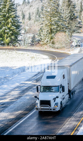 Big Rig white long haul semi carrello con la protezione della griglia del trasporto merci commerciali in dry van semi rimorchio guida su girando inverno nevoso dan umido Foto Stock