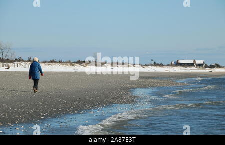 Old Lyme, CT / STATI UNITI D'America - 3 Marzo 2019: Lone donna camminando lungo la riva e ottenere qualche esercizio nonostante la conchiglia Foto Stock