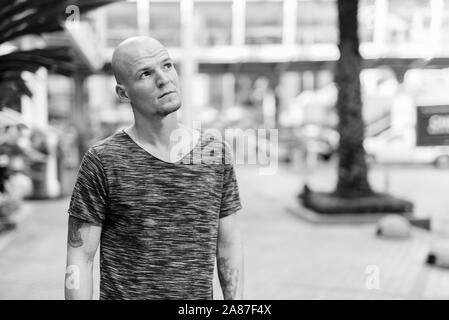 Bel giovane uomo calvo pensare al di fuori del centro commerciale Foto Stock