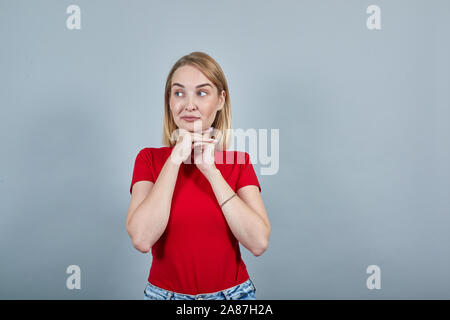 Ritratto di sorridente giovane donna cercando in disparte mettere mano prop fino sul mento Foto Stock