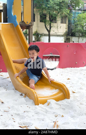 Bambino che gioca sul parco giochi all'aperto. Bambini a giocare sulla scuola o asilo nido cantiere. Foto Stock