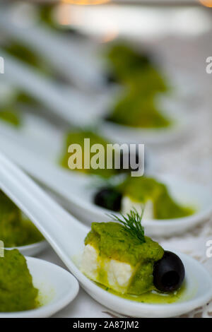 Gustosi e colorati antipasti verde essendo servito a cucchiaiate su di una piastra su un party Foto Stock