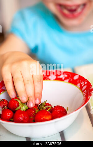 Close up della bambina tenuto dalla tazza di fragole. Foto Stock