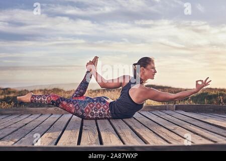 Giovane donna sulla spiaggia facendo esercizi yoga, Cape Town, Sud Africa Foto Stock