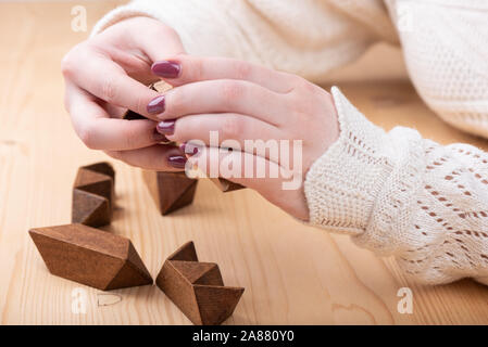 Ragazza raccoglie puzzle a forma di stella dodecaedro. Dodici facciate piccola a forma di stella dodecaedro al di sopra di un tavolo di legno. Copia dello spazio. Concetto di puzzle. Foto Stock