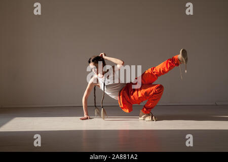 Bella donna con trecce danze di musica di colore arancione Foto Stock